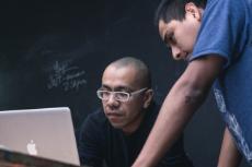 A student and a professor next to each other looking at a computer screen
